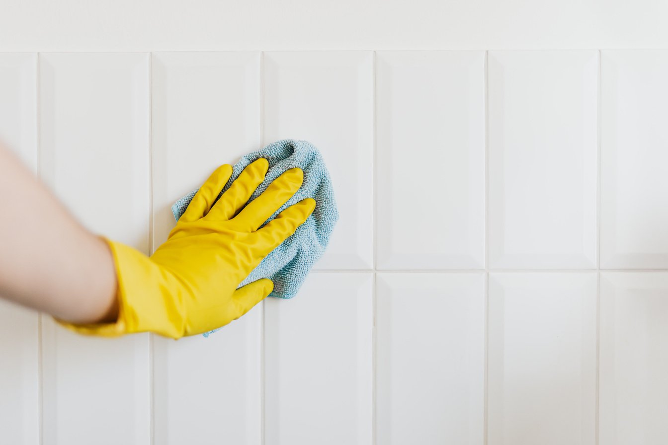 Crop person cleaning tiles with rag